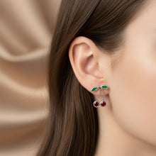 Charger l'image dans la galerie, A pair of silver-toned earrings on a textured light green. One earring features cherrie design, with a post and butterfly clasp.